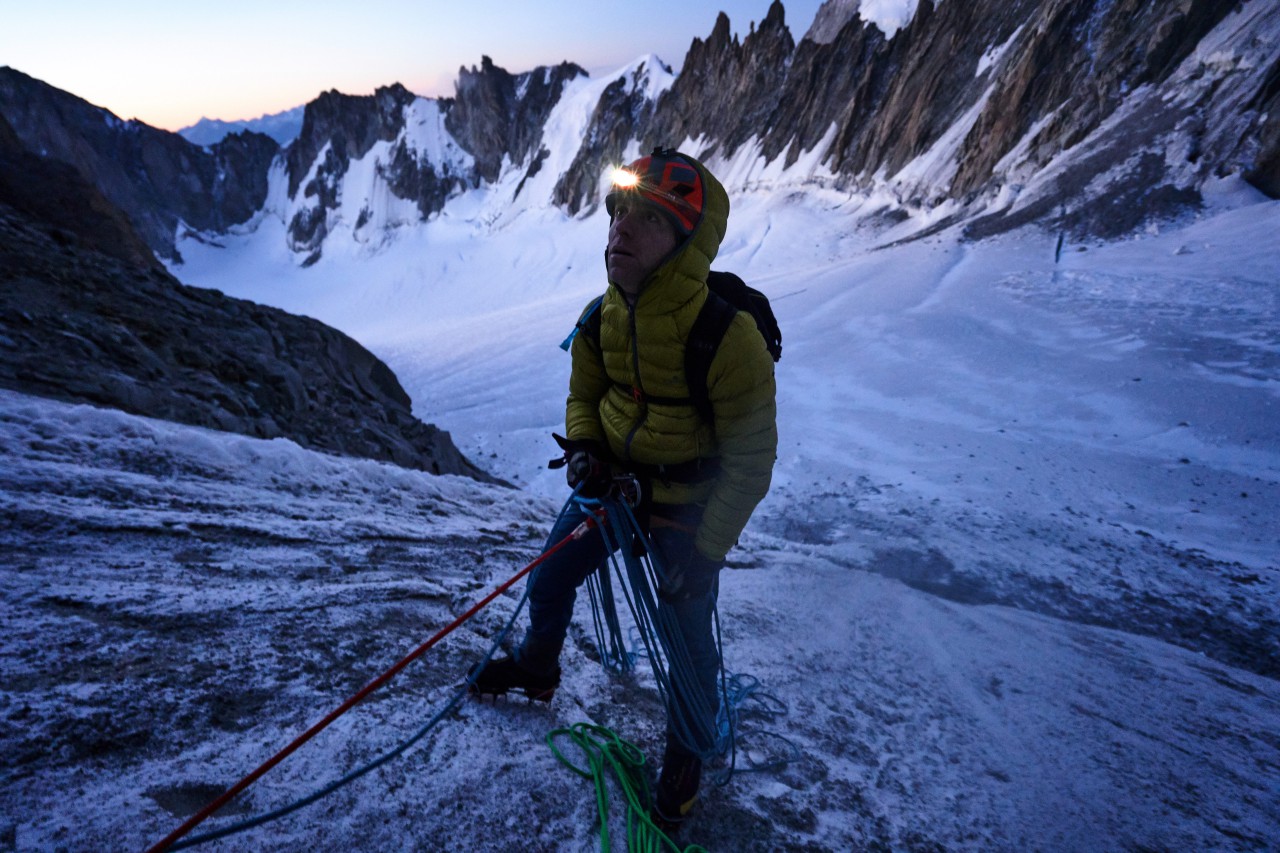 Willis Morris layering a Fenrir down jacket on a cold belay