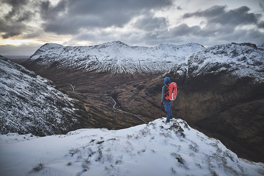 A walker standing on top of a hill overlooking Glen Coe