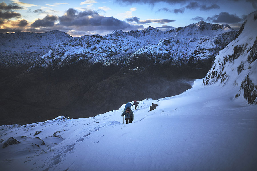 Two walkers on a snow slope on Am Bodach at dawn