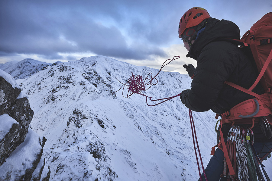 A climber throws a rope off Meall Dearg to abseil from