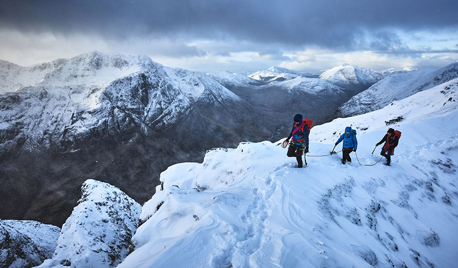 A team of three climbers on a snow slope on Aonach Eagach